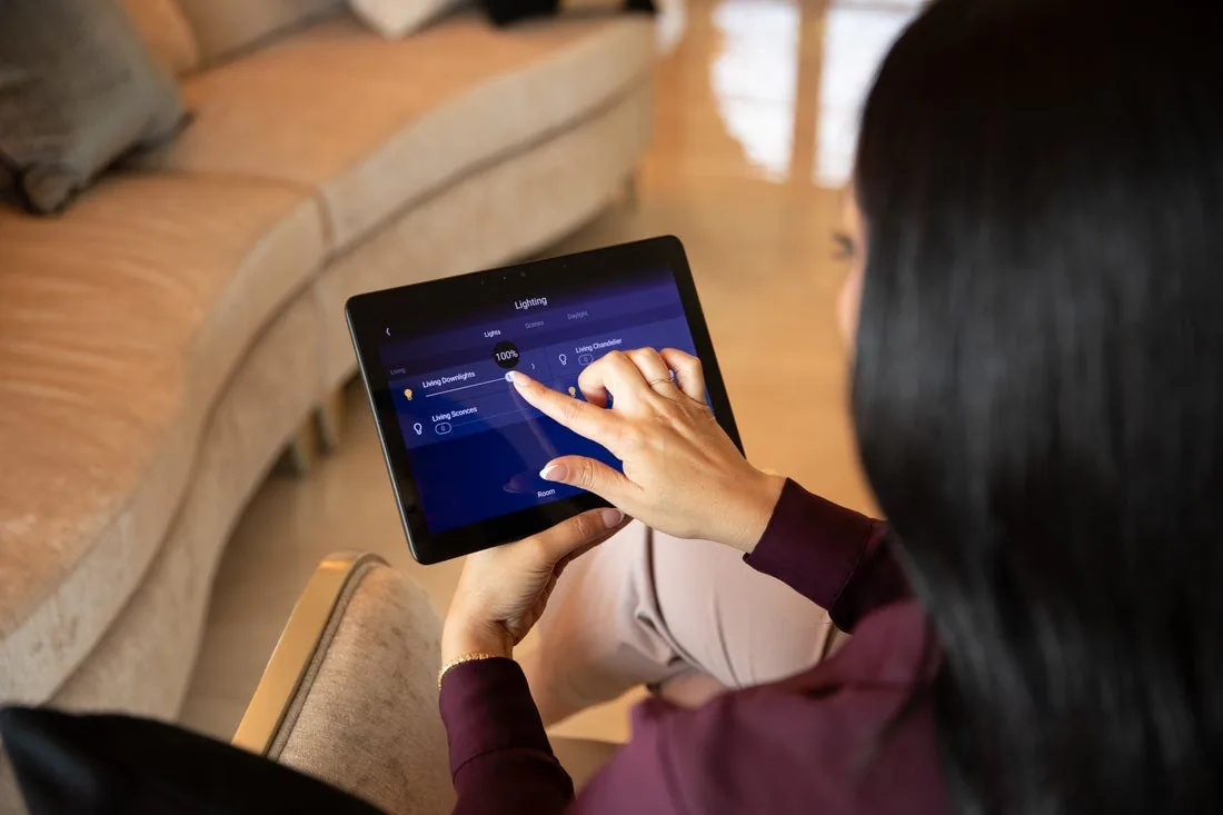 Homeowner adjusting lighting scenes on a Control4 tablet
