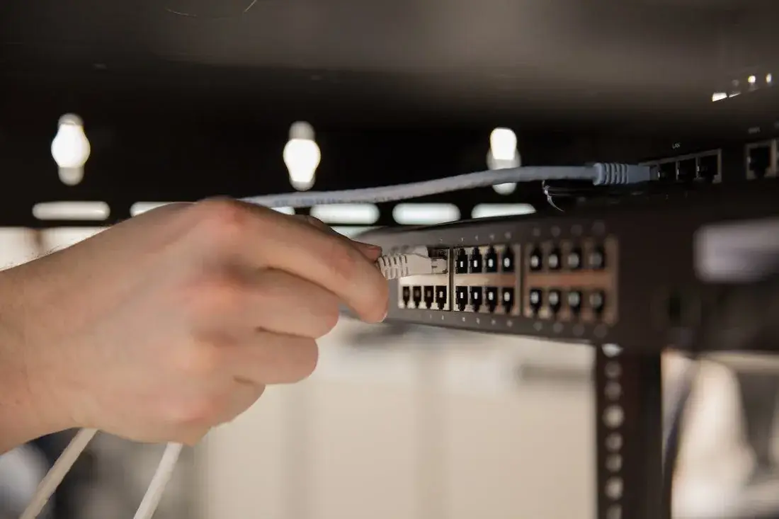Technician plugging an Ethernet cable into a home network switch