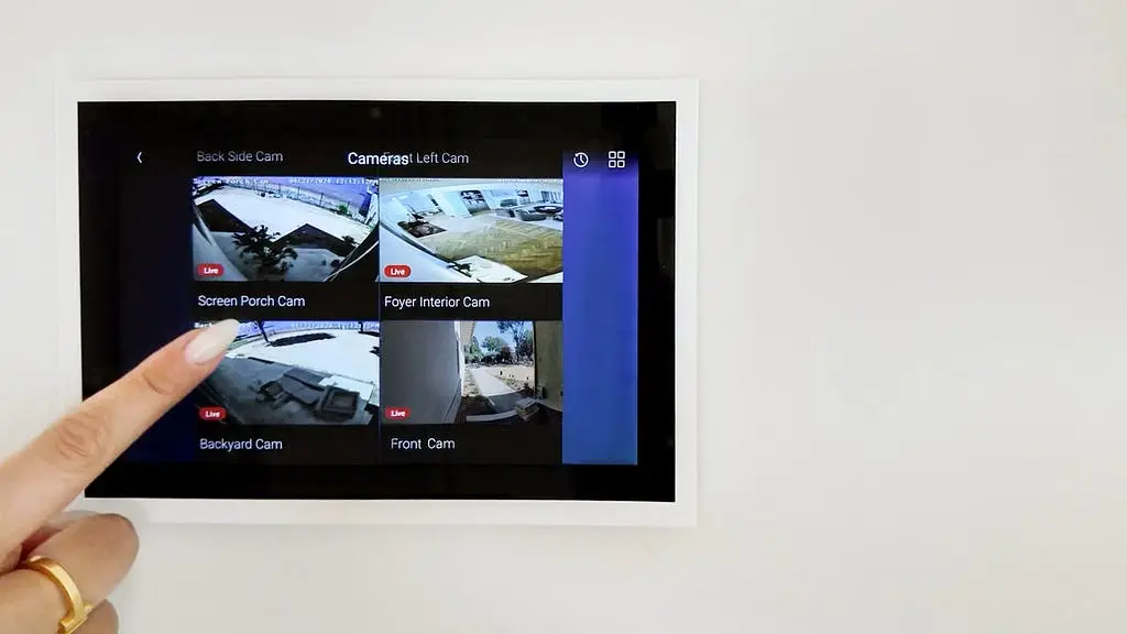 Wall-mounted touchscreen showing live security camera feeds around a home