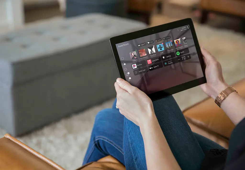 Homeowner using a tablet to control lighting, music, and climate from the sofa