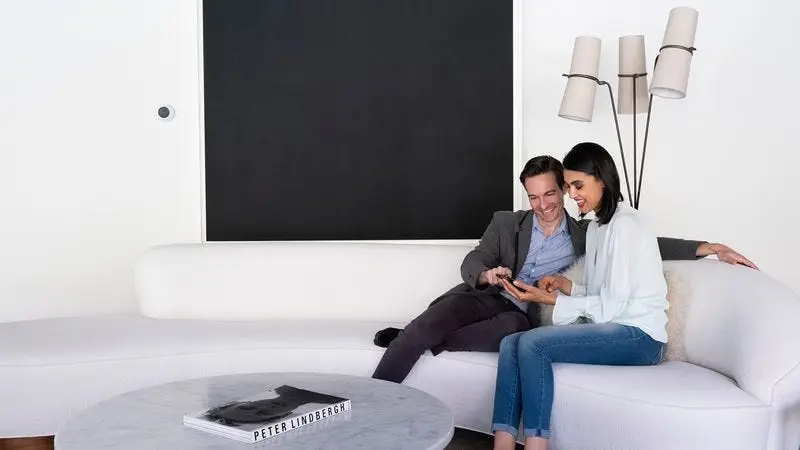 Couple sitting on a sofa reviewing a phone while planning their home